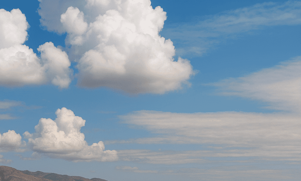 Almería Weather. Panoramic view of Almería beach under partly cloudy skies with calm sea and mountains in background