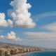 Almería Weather. Panoramic view of Almería beach under partly cloudy skies with calm sea and mountains in background