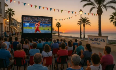 Community watching TVE Grand Prix on large outdoor screen in Balanegra, Almeria at sunset