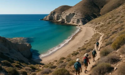 Pristine Cala de Enmedio beach surrounded by cliffs with hikers on the winding trail in Almeria