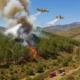 Aerial firefighting operation over forest fire near Laujar de Andarax, Almeria under clear Mediterranean daylight.