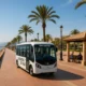 Electric tourist bus on Roquetas de Mar beach promenade with shaded seating and visitors.