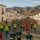 Runners in La Desértica race passing through a sunlit Almeria town street with arid hills.