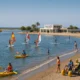 People enjoying various watersports at Nueva Almeria beach with inclusive activities and clear Mediterranean sky